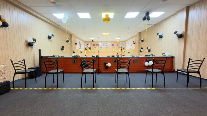 An empty firing line with numbered lanes and the Rudra Sports banner on the wall