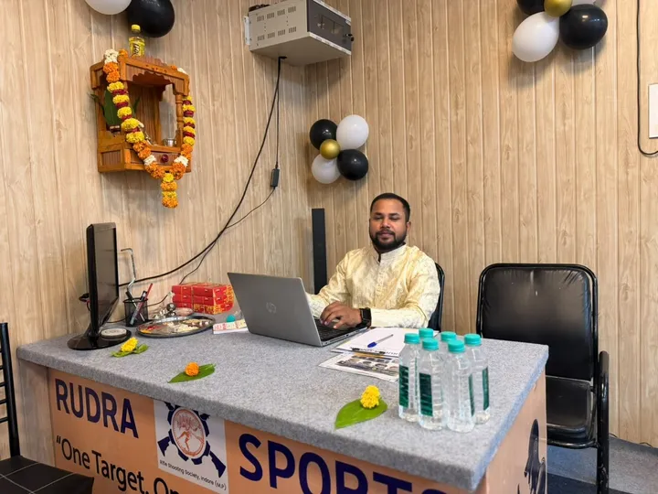 A staff member at the Rudra Sports registration desk, decorated with flowers and balloons
