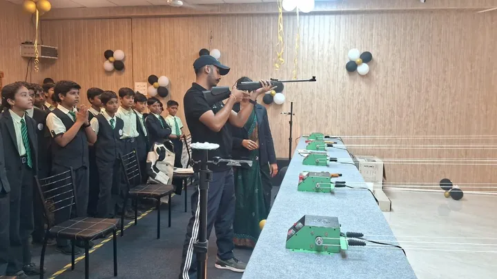 A coach demonstrating how to aim an air rifle while students in uniform watch